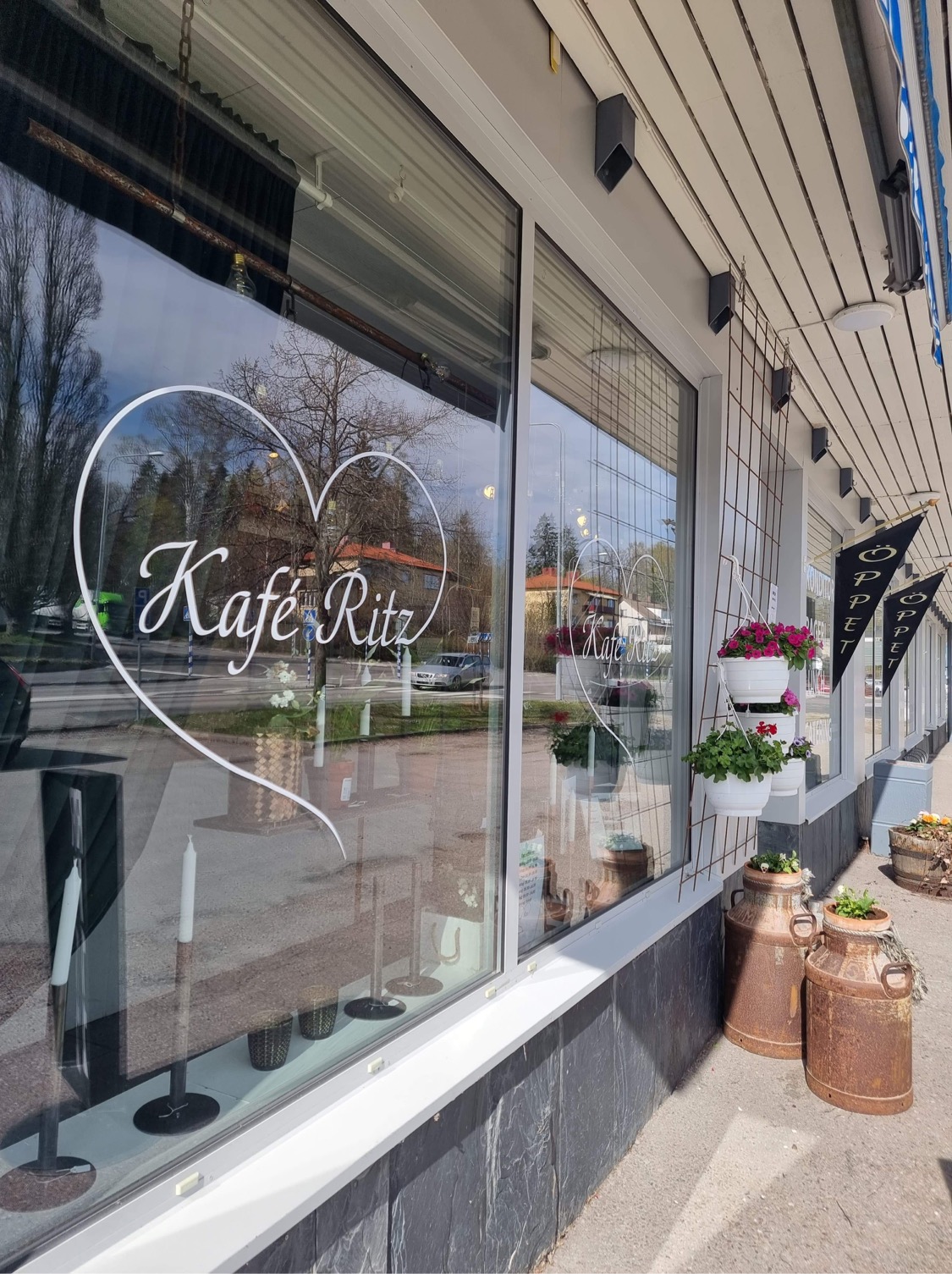 Kafé Ritz skyltfönster från utsidan med logotyp och blomster.